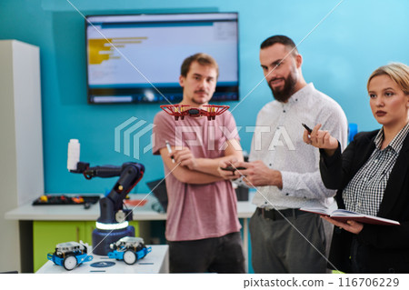 A group of students working together in a laboratory, dedicated to exploring the aerodynamic capabilities of a drone A group of students working together in a laboratory, dedicated to exploring the aerodynamic capabilities of a drone 116706229