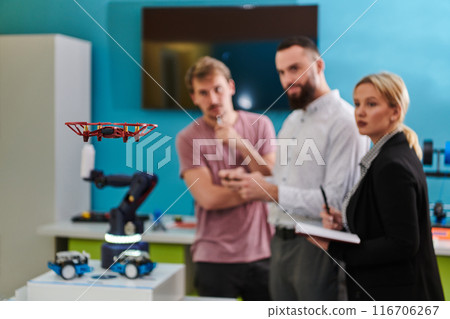 A group of students working together in a laboratory, dedicated to exploring the aerodynamic capabilities of a drone A group of students working together in a laboratory, dedicated to exploring the aerodynamic capabilities of a drone 116706267