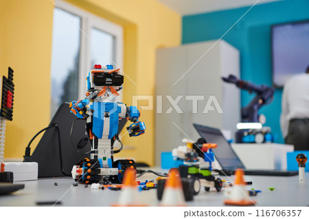 A student testing his new invention of a robotic arm in the laboratory, showcasing the culmination of his research and technological prowess. 116706357
