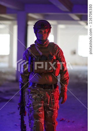 A professional soldier undertakes a perilous mission in an abandoned building illuminated by neon blue and purple lights A professional soldier undertakes a perilous mission in an abandoned building illuminated by neon blue and purple lights 116706380