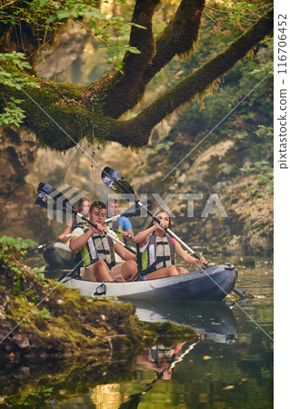 A group of friends enjoying having fun and kayaking while exploring the calm river, surrounding forest and large natural river canyons 116706452
