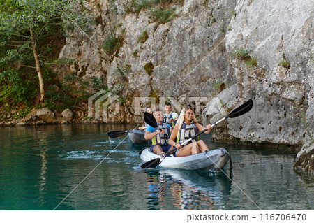 A group of friends enjoying having fun and kayaking while exploring the calm river, surrounding forest and large natural river canyons 116706470