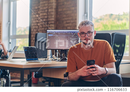 A modern businessman takes a relaxing break from work, using his smartphone to unwind and recharge during his pause 116706633