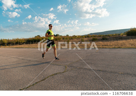 Triathlete in professional gear running early in the morning, preparing for a marathon, dedication to sport and readiness to take on the challenges of a marathon. Triathlete in professional gear running early in the morning, preparing for a marathon, dedication to sport and readiness to take on the challenges of a marathon. 116706638