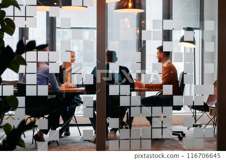 In a sleek glass office space, a team of business professionals engage in lively discussions and exchange strategic ideas, showcasing collaboration and innovation at the heart of modern corporate In a sleek glass office space, a team of business professionals engage in lively discussions and exchange strategic ideas, showcasing collaboration and innovation at the heart of modern corporate 116706645