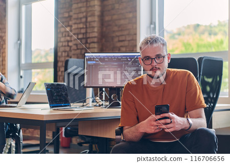 A modern businessman takes a relaxing break from work, using his smartphone to unwind and recharge during his pause A modern businessman takes a relaxing break from work, using his smartphone to unwind and recharge during his pause 116706656