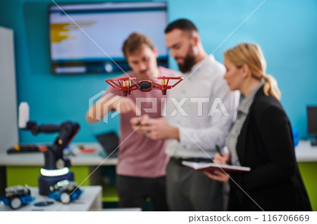 A group of students working together in a laboratory, dedicated to exploring the aerodynamic capabilities of a drone 116706669
