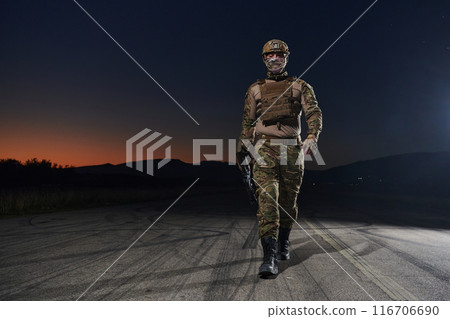 A professional soldier in full military gear striding through the dark night as he embarks on a perilous military mission 116706690
