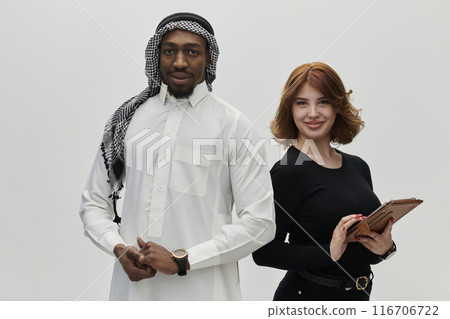 Arabic entrepreneur and a businesswoman, exuding confidence and unity, pose together against a clean white backdrop, symbolizing a dynamic partnership characterized by ambition, innovation, and 116706722