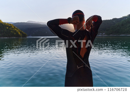 Authentic triathlon athlete getting ready for swimming training on lake Authentic triathlon athlete getting ready for swimming training on lake 116706728