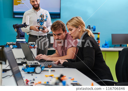 A group of colleagues working together in a robotics laboratory, focusing on the intricate fields of robotics and 3D printing. Showcase their dedication to innovation, as they engage in research 116706846