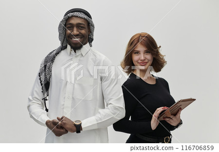 Arabic entrepreneur and a businesswoman, exuding confidence and unity, pose together against a clean white backdrop, symbolizing a dynamic partnership characterized by ambition, innovation, and 116706859