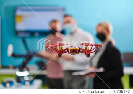 A group of students working together in a laboratory, dedicated to exploring the aerodynamic capabilities of a drone A group of students working together in a laboratory, dedicated to exploring the aerodynamic capabilities of a drone 116706927
