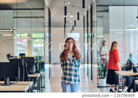 A portrait of a young businesswoman with modern orange hair captures her poised presence in a hallway of a contemporary startup coworking center, embodying individuality and professional confidence. A portrait of a young businesswoman with modern orange hair captures her poised presence in a hallway of a contemporary startup coworking center, embodying individuality and professional confidence. 116706989
