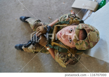 A woman in a professional military uniform sits in an abandoned building, ready for a dangerous mission, exuding bravery and determination 116707000