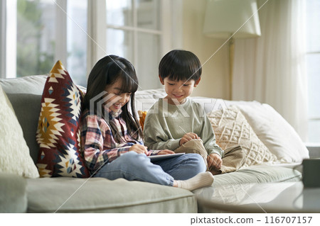 two cute little asian kids using digital tablet at home two cute little asian kids using digital tablet at home 116707157