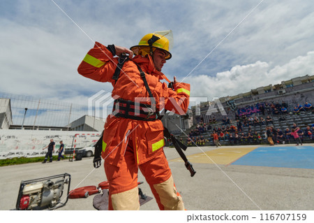 In a dynamic display of synchronized teamwork, firefighters hustle to carry, connect, and deploy firefighting hoses with precision, showcasing their intensive training and readiness for challenging 116707159