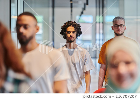 A diverse group of business people walking a corridor in the glass-enclosed office of a modern startup, including a person in a wheelchair and a woman wearing a hijab, showing a dynamic mix of A diverse group of business people walking a corridor in the glass-enclosed office of a modern startup, including a person in a wheelchair and a woman wearing a hijab, showing a dynamic mix of 116707207