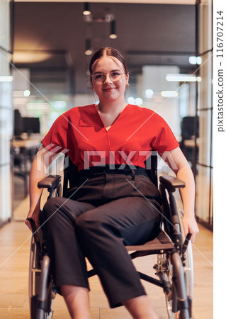A modern young businesswoman in a wheelchair is surrounded by an inclusive workspace with glass-walled offices, embodying determination and innovation in the business world A modern young businesswoman in a wheelchair is surrounded by an inclusive workspace with glass-walled offices, embodying determination and innovation in the business world 116707214