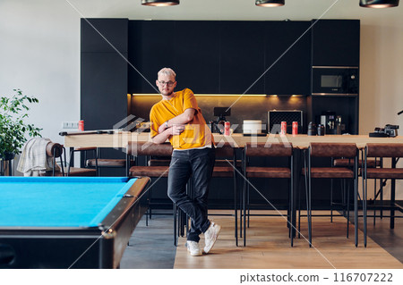 A man takes a brief rest from work in a modern startup coworking center, using the moment to recharge and relax with technology by his side. 116707222