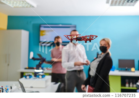 A group of students working together in a laboratory, dedicated to exploring the aerodynamic capabilities of a drone 116707235