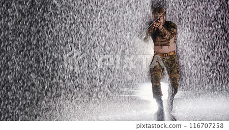 Army soldier in Combat Uniforms with an assault rifle, plate carrier and combat helmet going on a dangerous mission on a rainy night. 116707258