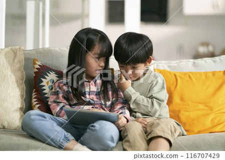 two cute little asian kids using digital tablet at home 116707429