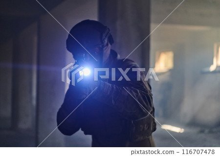 A professional soldier in an abandoned building shows courage and determination in a war campaign 116707478