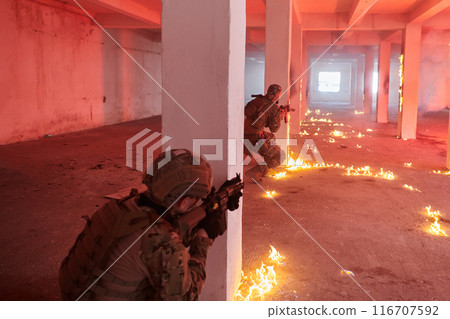 A group of professional soldiers bravely executes a dangerous rescue mission, surrounded by fire in a perilous building. 116707592