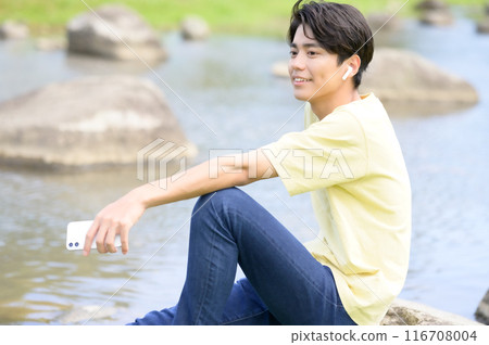 夏天,一名男子在水邊乘涼時操作智慧型手機 夏天,一名男子在水邊乘涼時操作智慧型手機 116708004