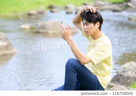 夏天,一名男子在水邊乘涼時操作智慧型手機 夏天,一名男子在水邊乘涼時操作智慧型手機 116708008