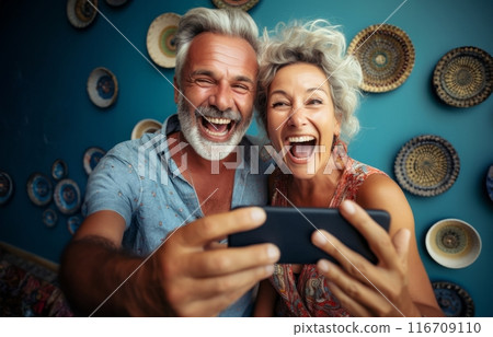 An elderly couple captures joyful moments at home using a smartphone, embracing modern technology for shared memories and social media moments.Generated image 116709110