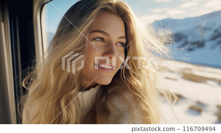 Enraptured by the snowy tableau, a woman's smile reflects the joy of being alone with her thoughts, savoring the tranquility of the train and the beauty of the winter scenery 116709494