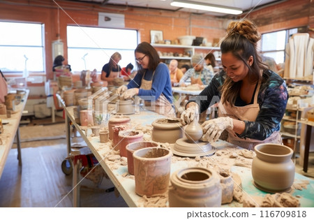 A diverse group of people come together to learn the art of pottery-making in a workshop, receiving instruction and guidance on sculpting clay into various vessels and forms.Generated image 116709818