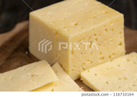 a piece of cheese with holes on the table 116710164