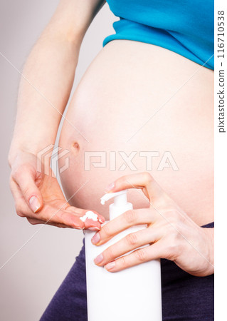 Pregnant woman applying moisturizing lotion on belly, avoid stretch marks 116710538