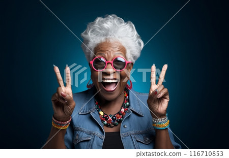 An elderly, modern African American woman with stylish grey hair is captured against a dark background, exuding joy and energy as she gracefully simulates aspects of contemporary senior living through 116710853