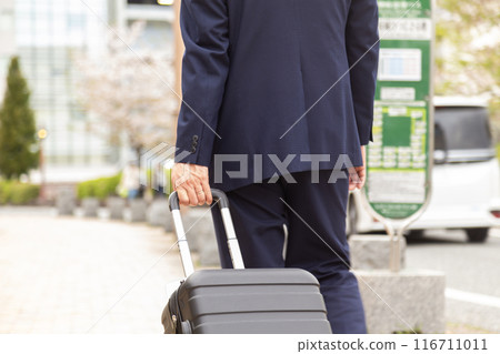 Businessman walking down the sidewalk with a suitcase 116711011