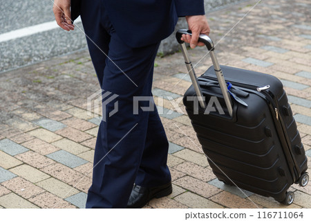 Businessman walking down the sidewalk with a suitcase Businessman walking down the sidewalk with a suitcase 116711064