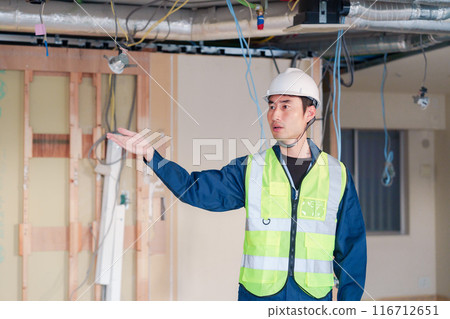 A male carpenter working in safety clothing at a construction site 116712651