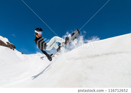 Young pro snowboarder riding the half pipe in mountain snow park, sliding and spraying on the halfpipe wall in sunny winter Young pro snowboarder riding the half pipe in mountain snow park, sliding and spraying on the halfpipe wall in sunny winter 116712652