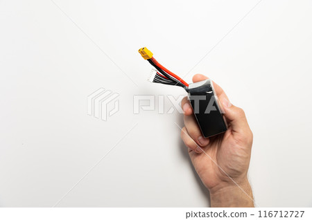 A man's hand holds a six-cell Lithium Polymer battery. On a white background. Lithium technology 116712727