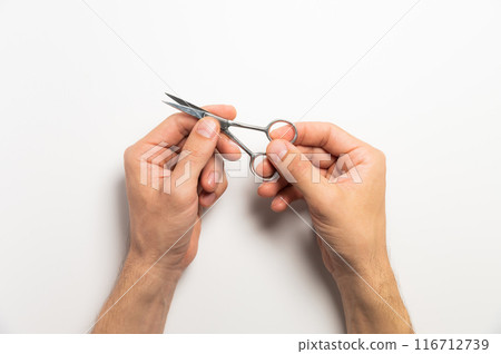 man with beautiful nails holds manicure scissors on a white background man with beautiful nails holds manicure scissors on a white background 116712739