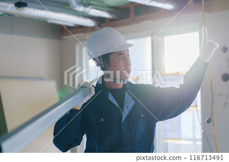 Male craftsman carrying materials at a construction site 116713491