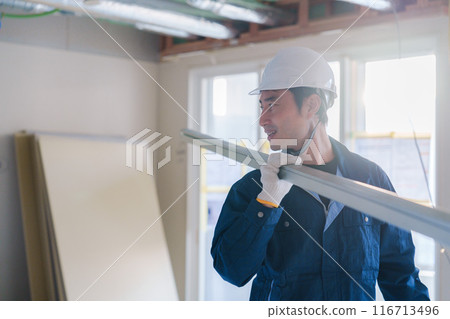 Male craftsman carrying materials at a construction site 116713496