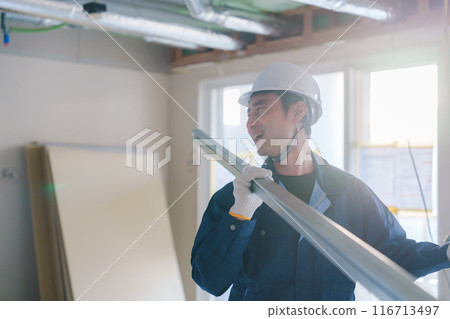 Male craftsman carrying materials at a construction site Male craftsman carrying materials at a construction site 116713497