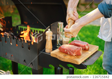 A close-up view of hands using a hand mill to season beef steak with sea salt A close-up view of hands using a hand mill to season beef steak with sea salt 116715842