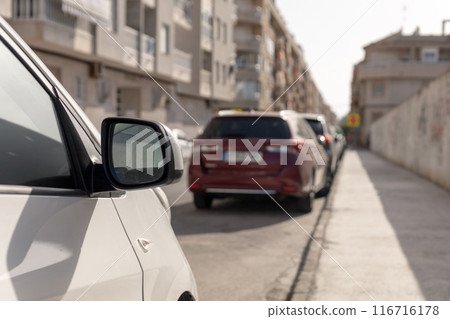 Line of parked cars along a narrow city street. Perfect for content related to urban transport, city living, automotive articles, or traffic management strategies. Parking price. 116716178