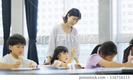 A teacher instructing elementary school students studying 116716215
