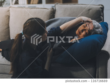 happy family Granddaughter takes care of her grandmother with warm cloths sitting on the sofa. happy family Granddaughter takes care of her grandmother with warm cloths sitting on the sofa. 116716689